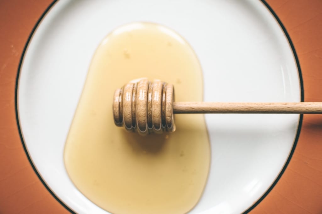 Honiglöffel und Honig auf einem weißen Teller