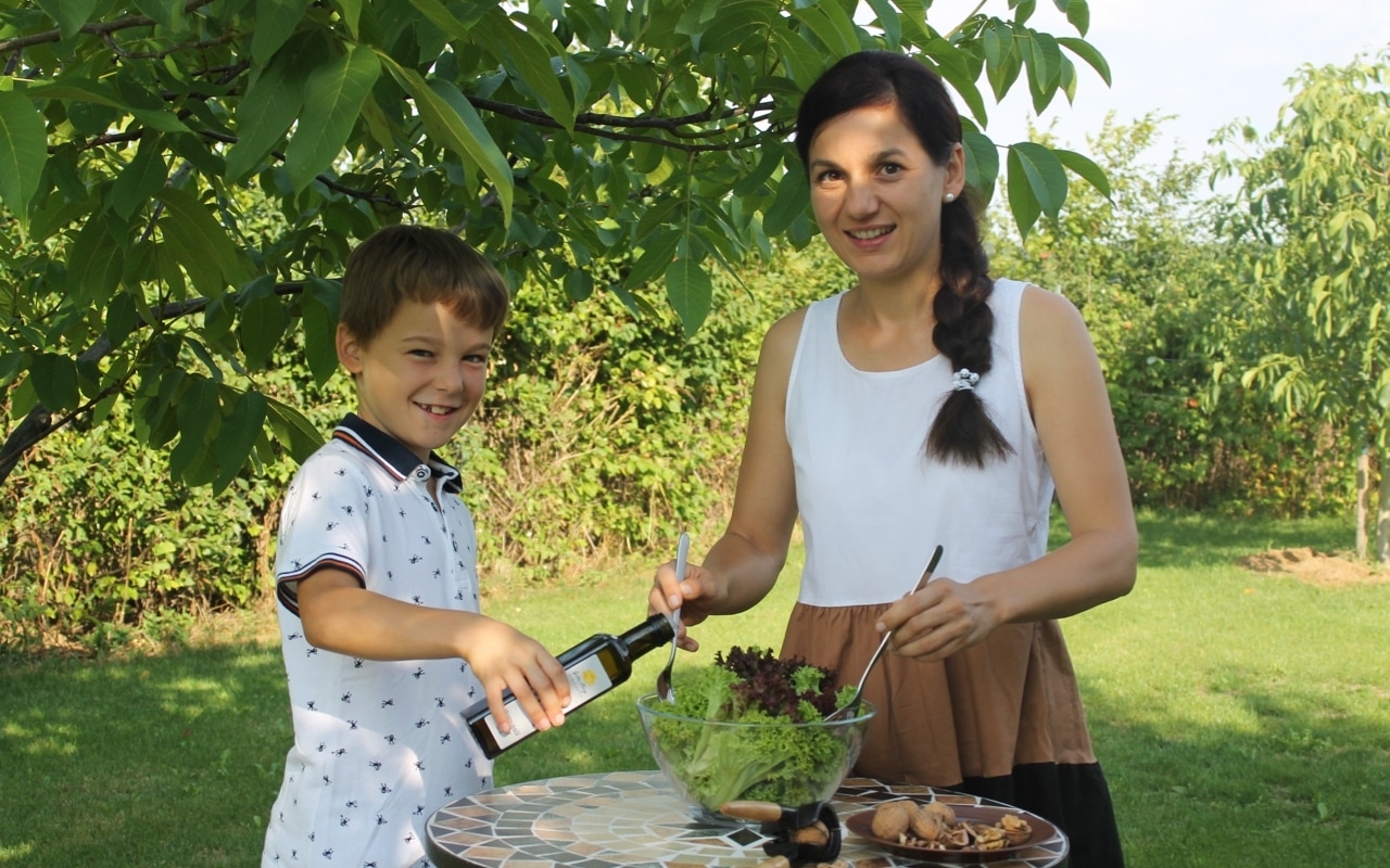 Frau und Kind würzen Salat mit Walnussöl von der Walnuss Manufaktur