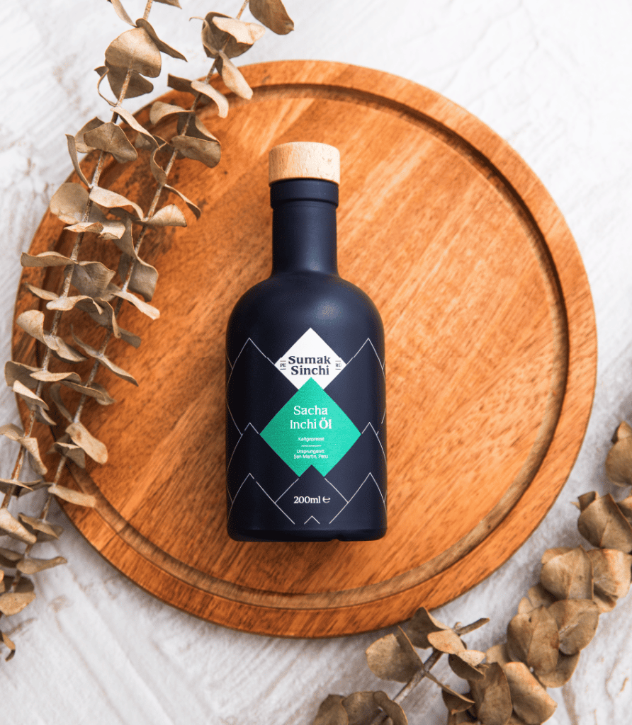 Schwarze Sacha Inchi Öl Flasche von Sumak Sinchi auf dunkelbraunem Holzbrett