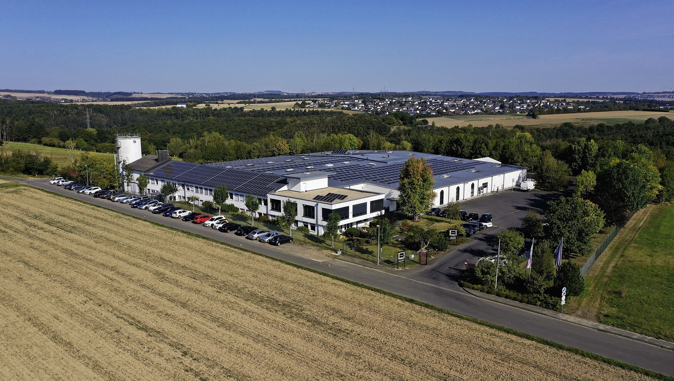 Der Firmensitz von Wajos am Feldrand und umgeben von Wald. Auf dem Dach befinden sich Solaranlagen.