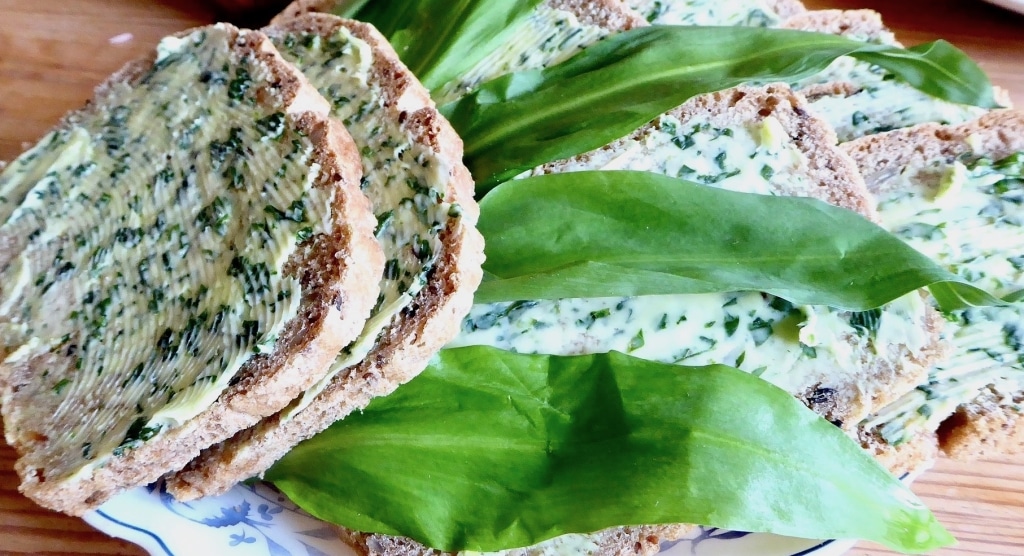 Brote mit Bärlauchbutter auf einem blau-weißen Teller garniert mit frischen Bärlauchblättern