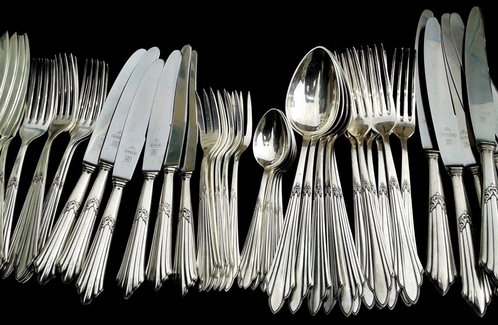 Glänzendes Silberbesteck -nebeneinander Gabeln, Messer, Löffel, Teelöffel und Kuchengabeln