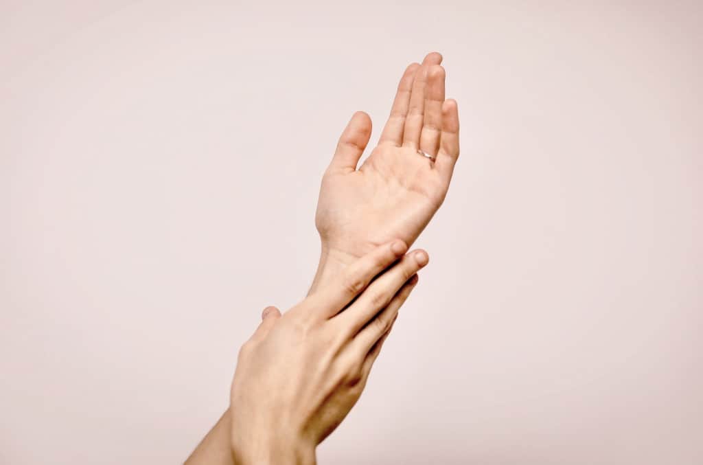 Zwei Hände recken sich in die Luft vor rosa-weißem Hintergrund